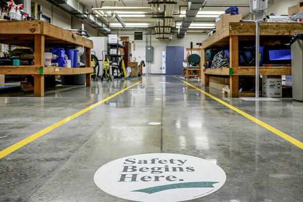 A campus workshop with a decal on the floor that reads "Safey Begins Here."