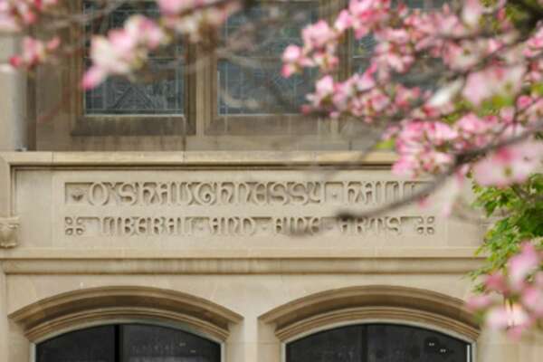 A view of the O'Shaughnessy Hall exterior entrance to the Great Hall surrounded by flowering trees