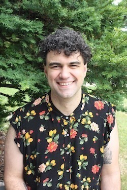 Andrew Evans: short curly dark hair, and sleeveless flowery top